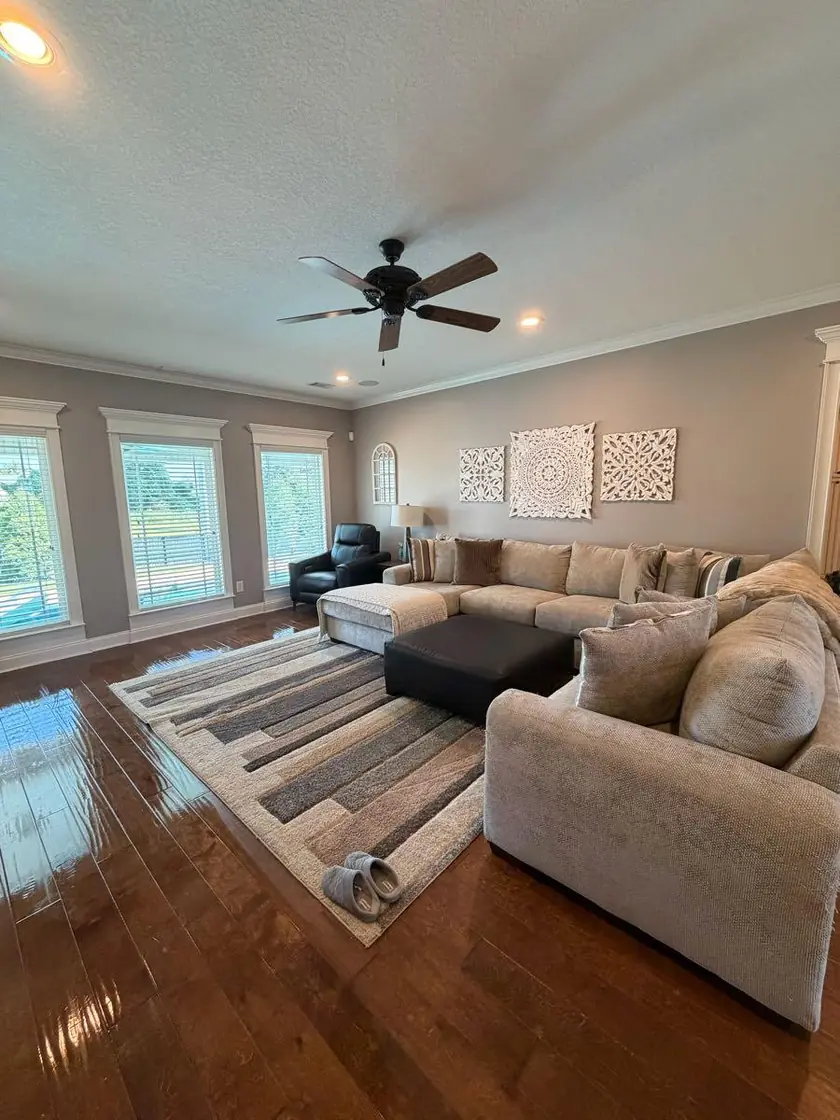 A living room with a sectional sofa and polished wood floors
