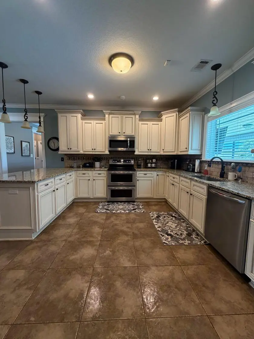 A kitchen with white cabinets and a clear tiled floor