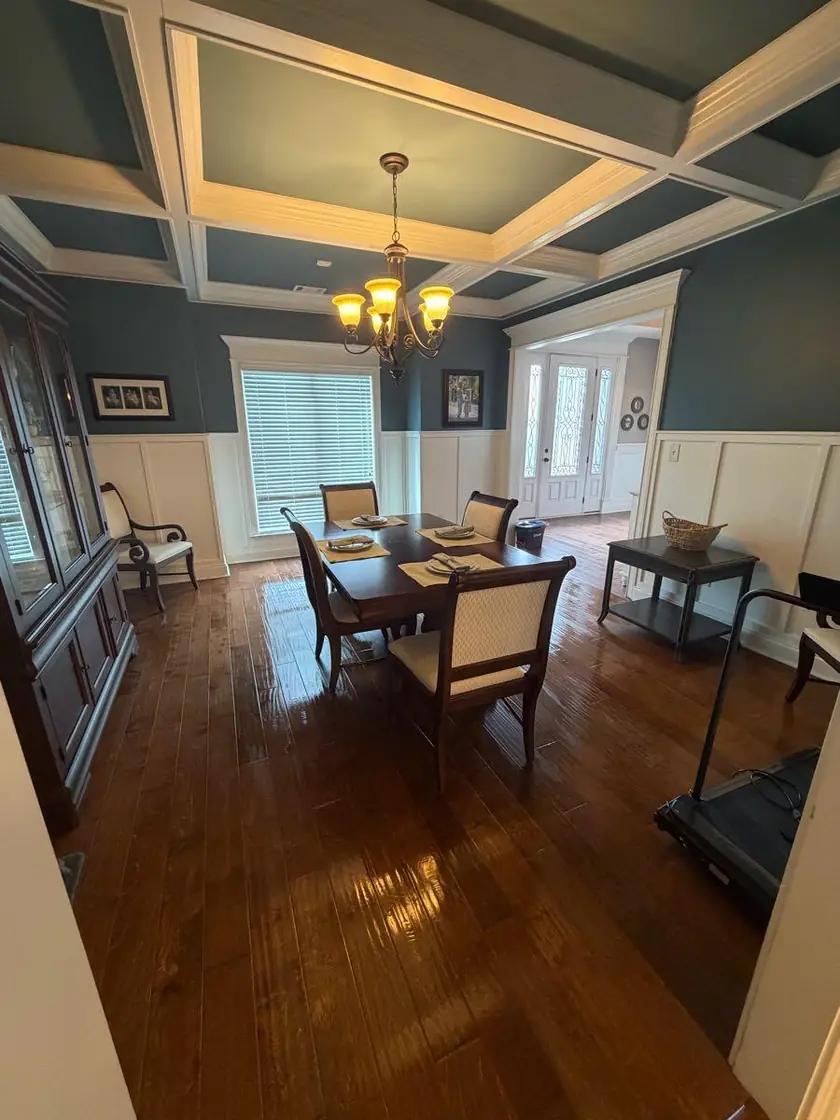 A dining room under a coffered ceiling with a chandelier