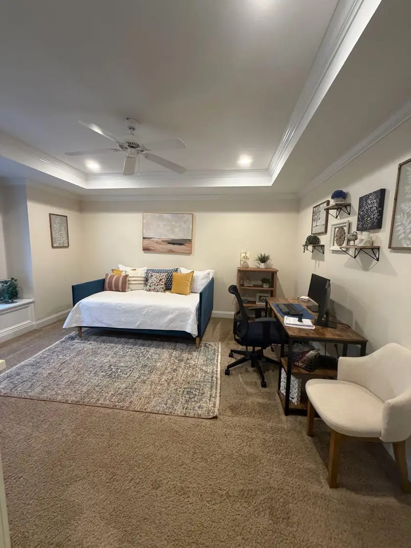 A bedroom with a made bed and a desk in the corner