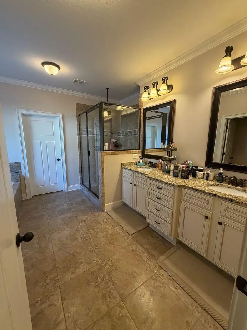 A primary bathroom with a double vanity and a walk in shower
