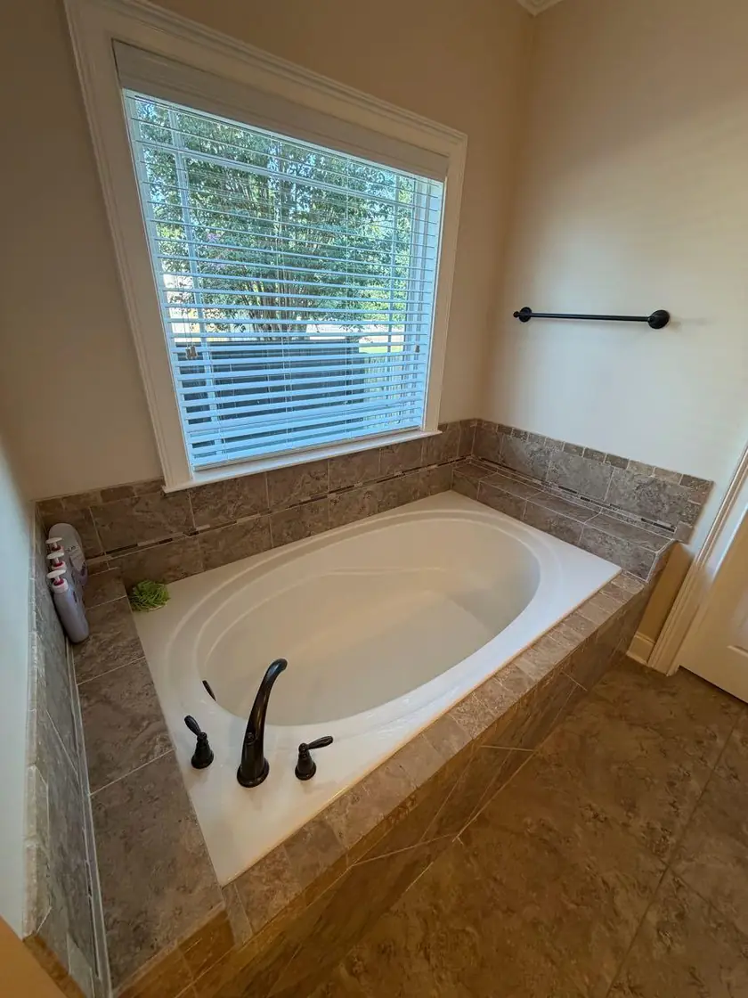 A garden tub set into tile below a shuttered window